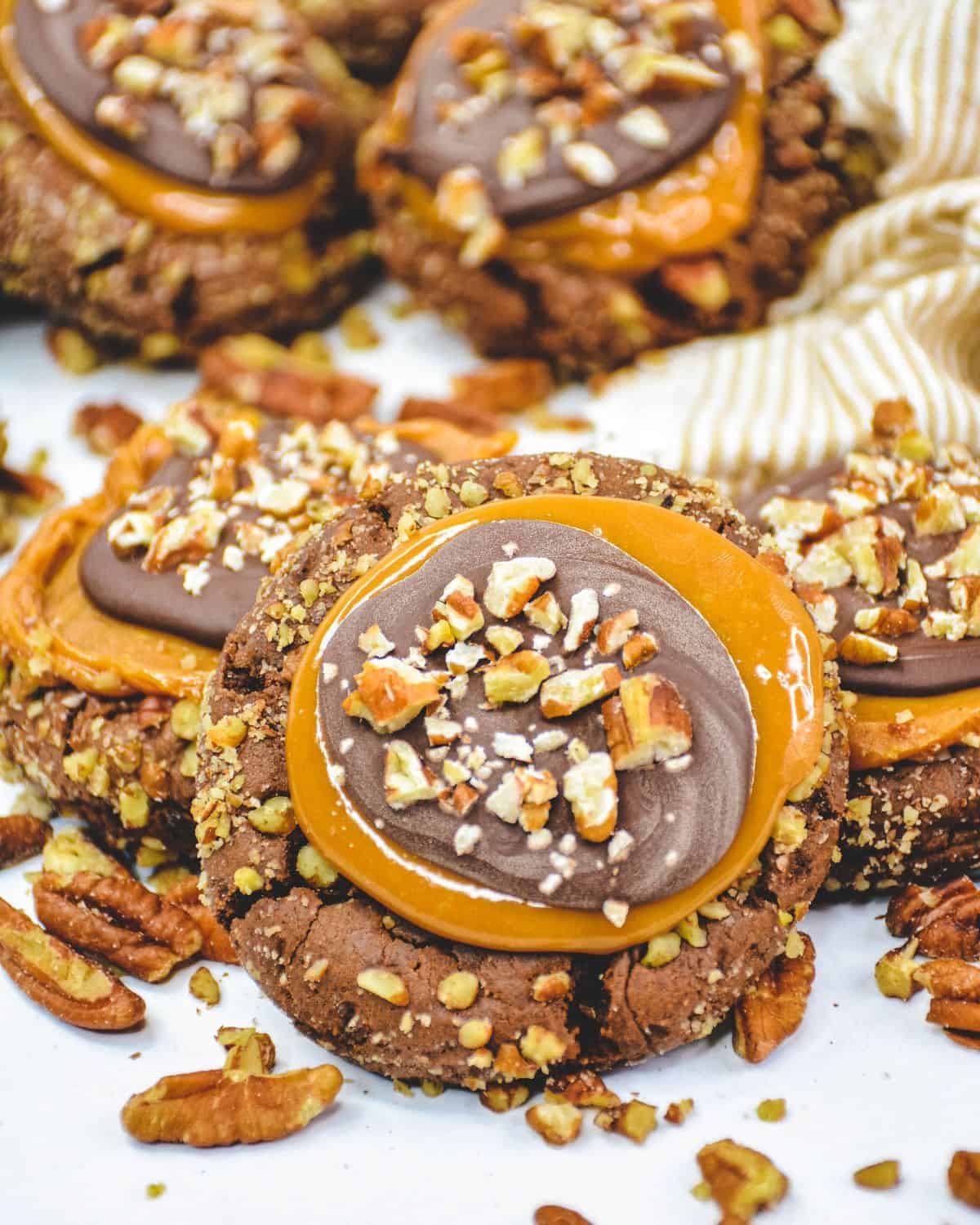 Chocolate cookies with pecans and topped with a caramel layer and more chopped pecans to make Crumbl Turtle cookies.