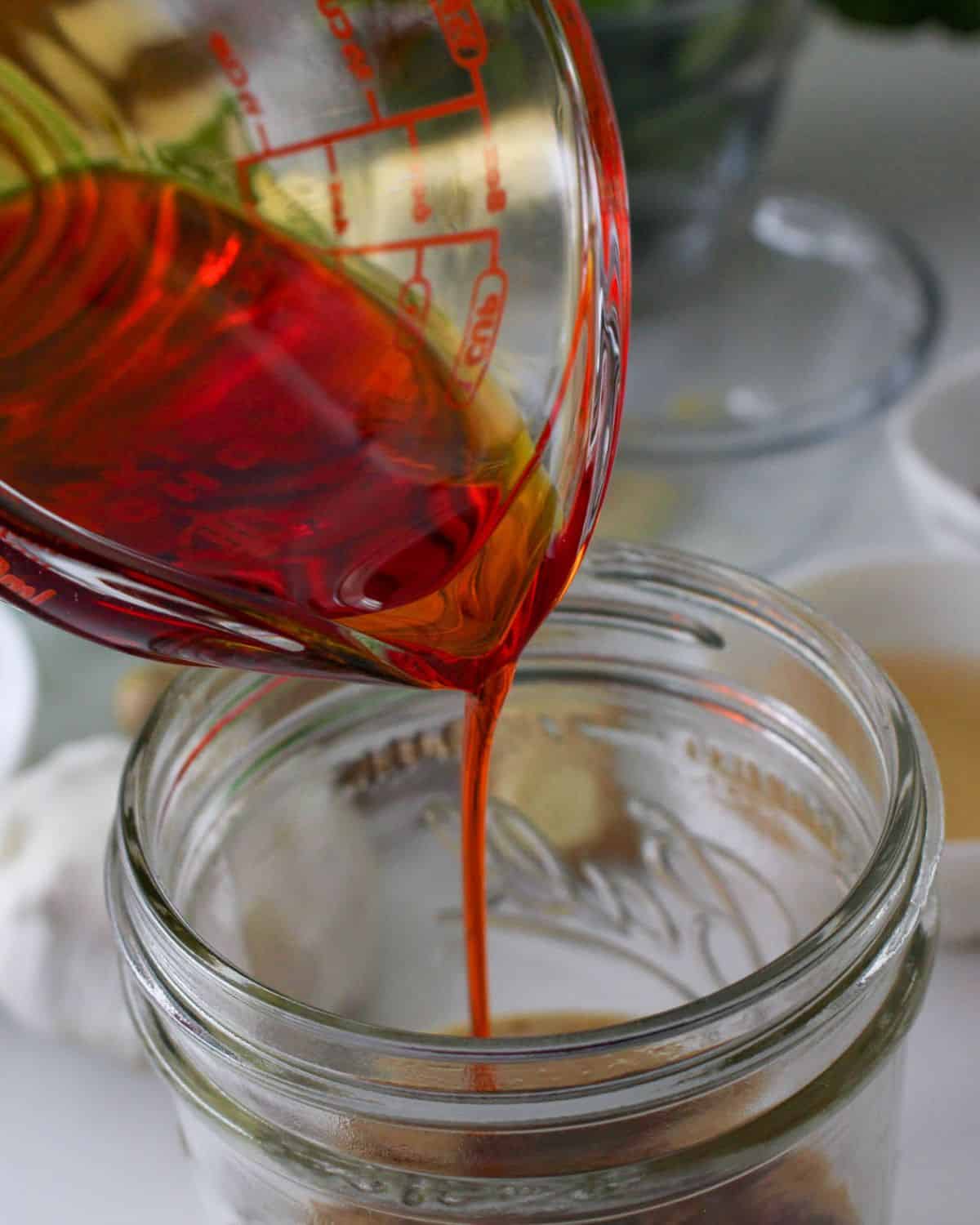 A jar with chili oil being poured in to make dan dan noodle sauce.