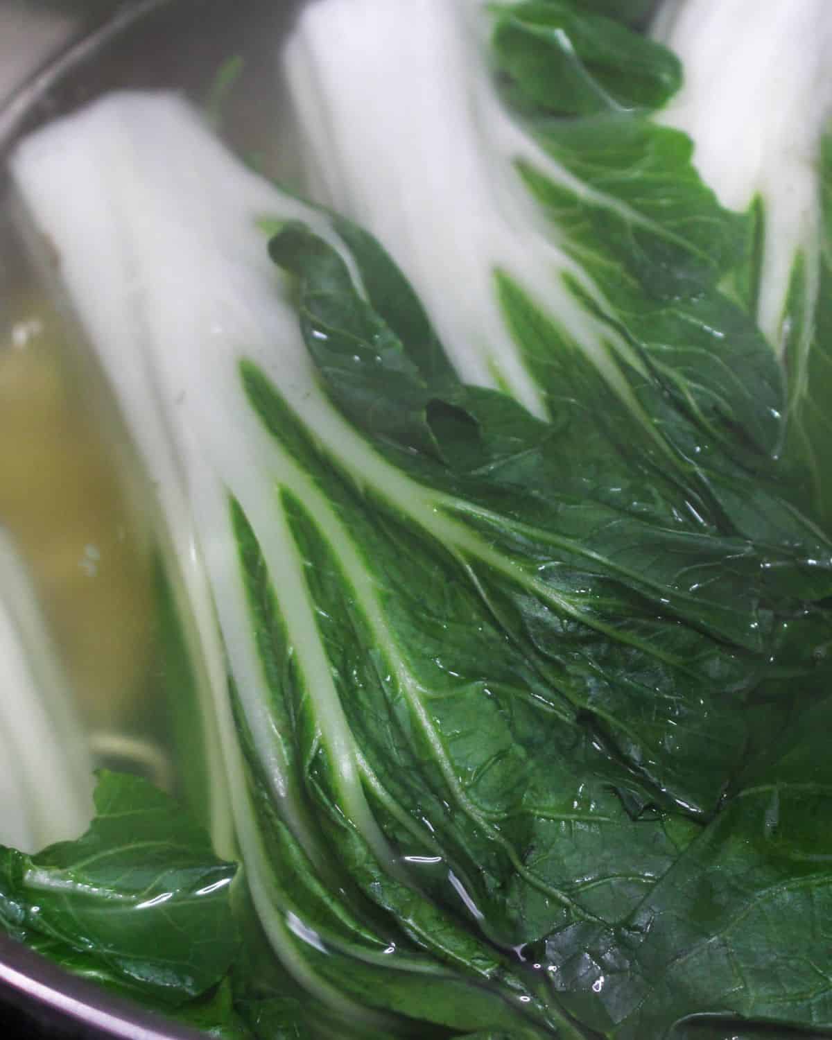 Bok choy and ramen noodles cooked to make a bowl of dan dan noodles. 