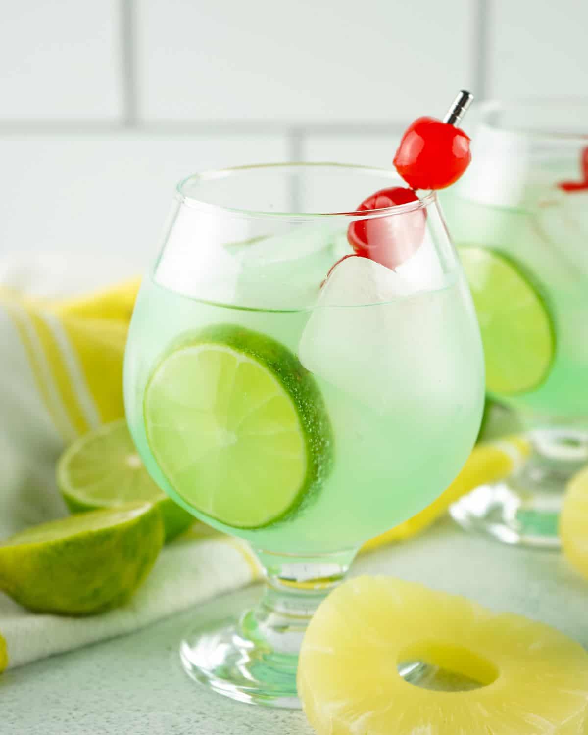 Tipsy mermaid cocktail ina glass with cherries and limes. 