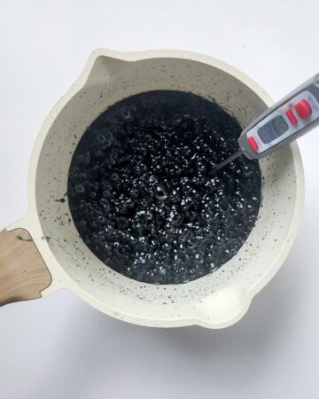 A large mixing bowl with candy sugar with black dye in the bowl to make candy apples. 