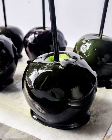 Black candy apples with a candy coating on the green apples. 