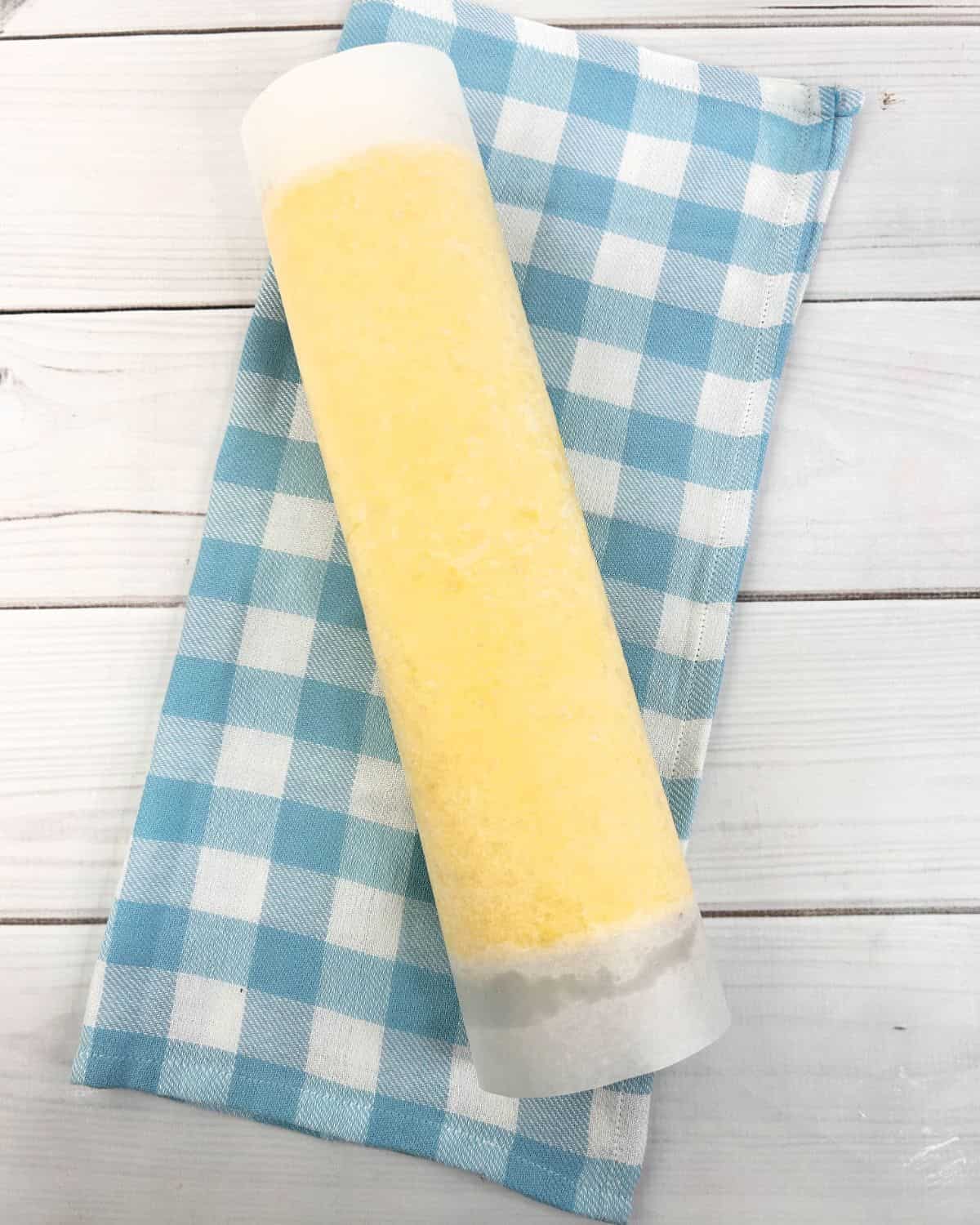 A lemon roll cake rolled up in parchment paper forming the roll.