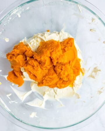 The glass bowl with two blocks of cream cheese and pumpkin puree. 