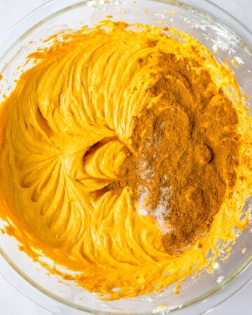 A mixture of pumpkin puree and cream whipped together with the addition of pumpkin spice, cinnamon, and salt in the bowl. 