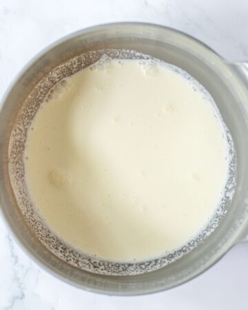 A large stainless steel mixing bowl with heavy cream in the bowl. 