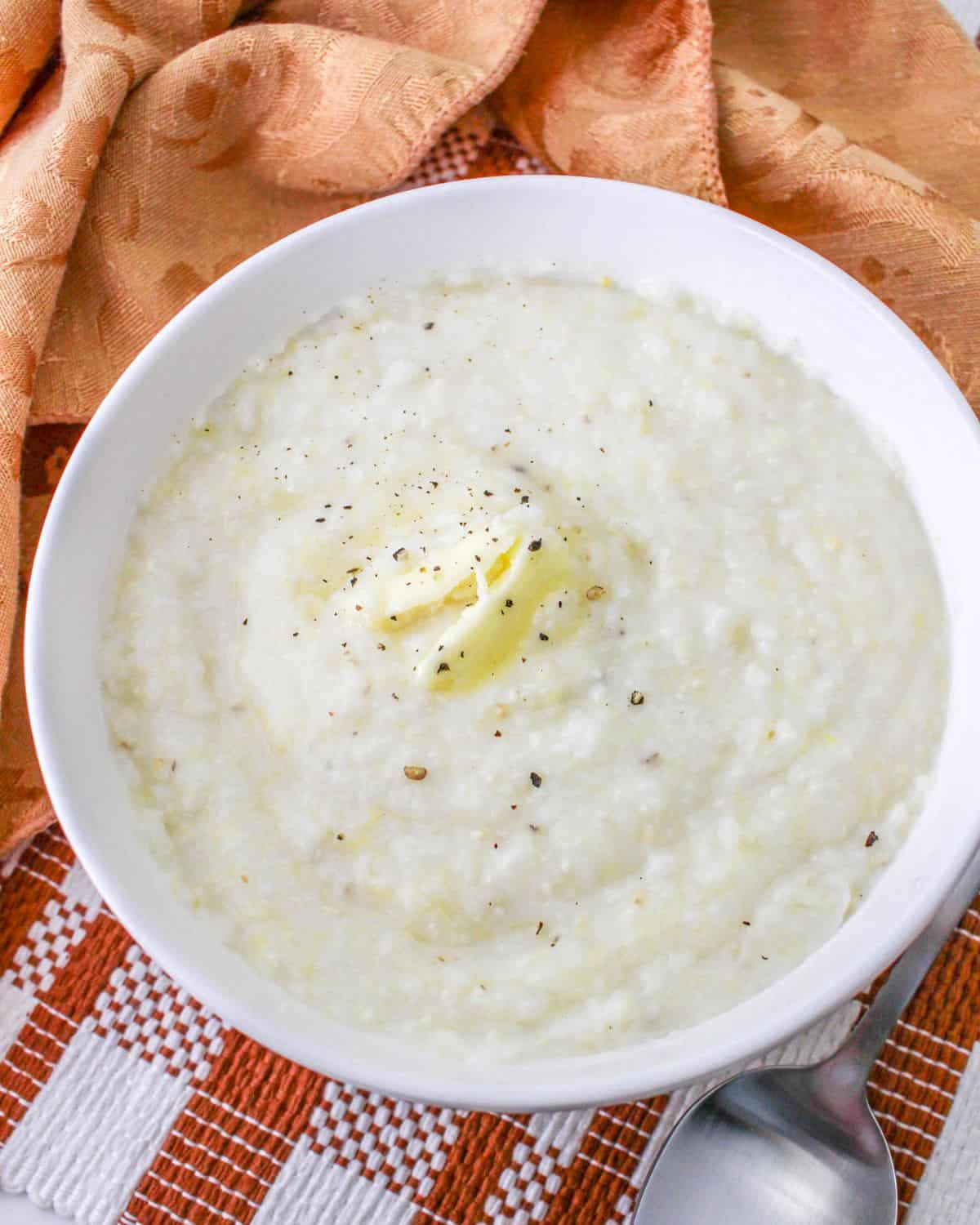 A bowl of grits made in the crock pot with a pat of butter on the grits.