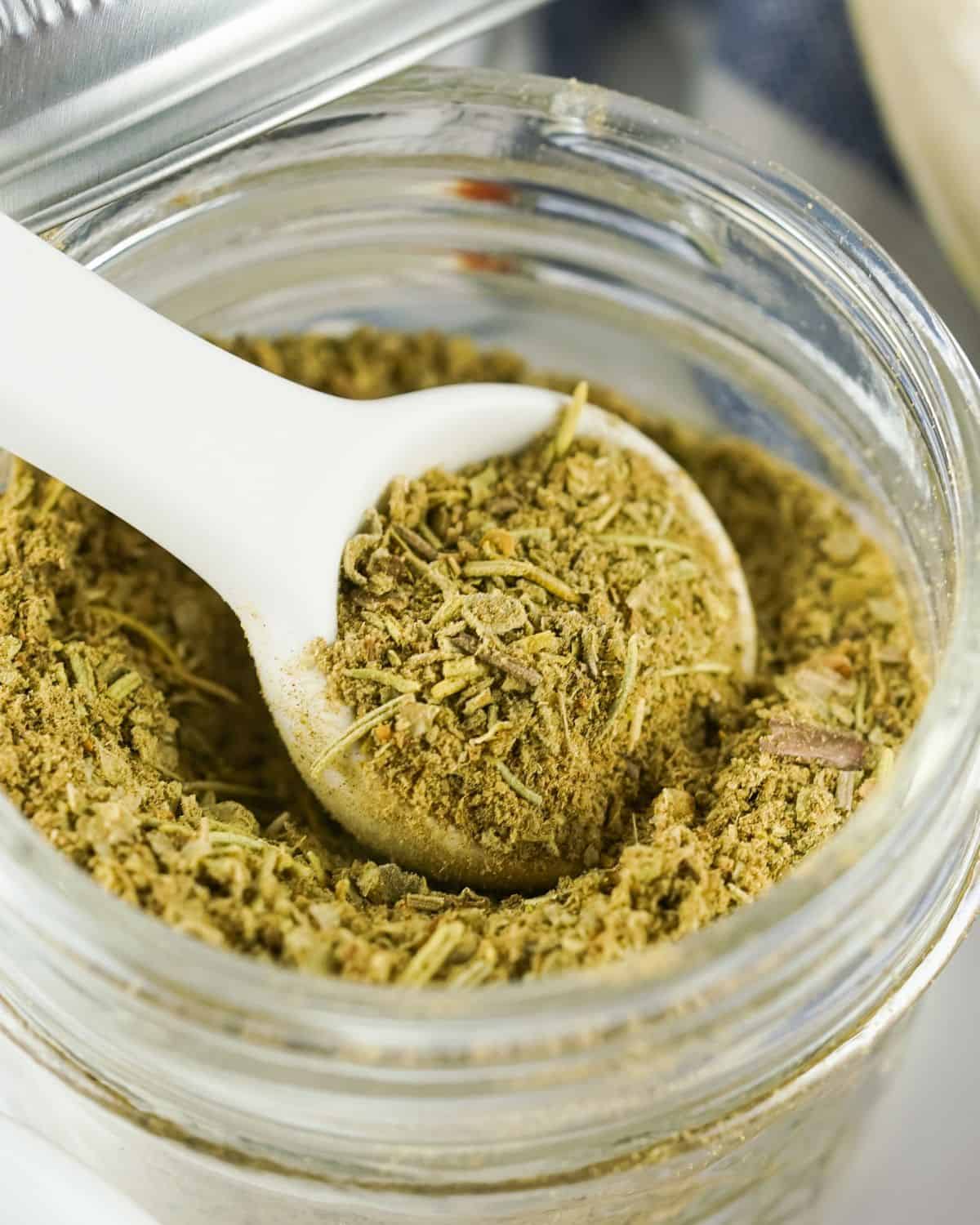 Homemade Poultry Seasoning Rub in a mason jar with a white spoon.