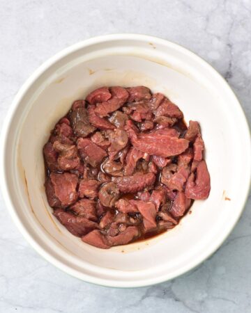 Sliced beef in a marinade to make beef and broccoli.