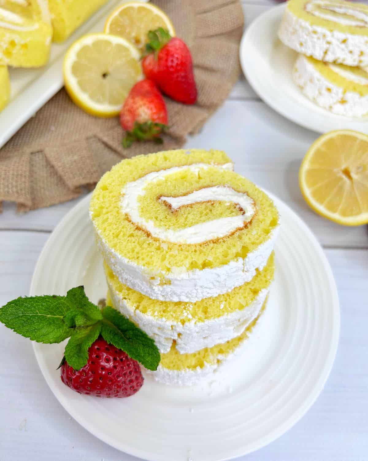 Sliced rolled emon cake on a plate with a creamy filling. 