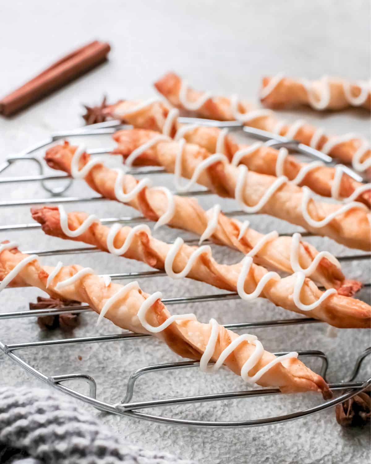 A wire rack with puff pastry twists filled with an apple pie filling.