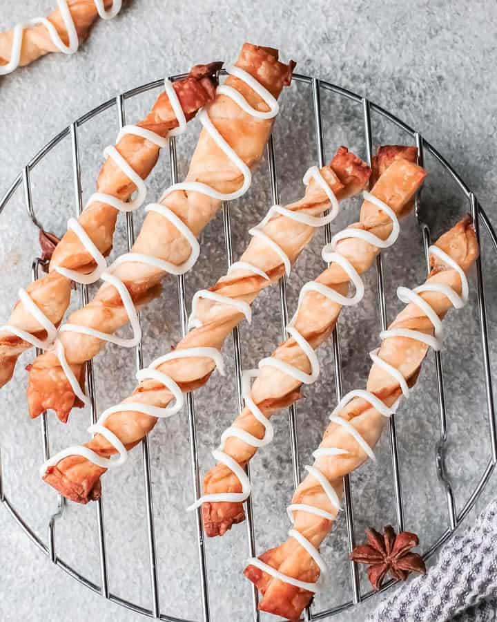 Apple puff pastry twists on a wire rack.