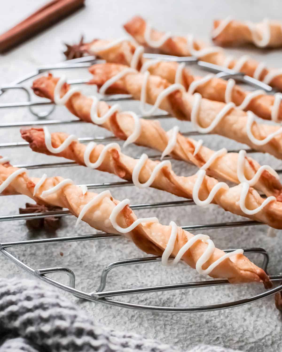 Twisted puff pastry filled with apple pie filling on a wire rack.