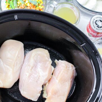 Chicken breasts in the vessel of a slow cooker.
