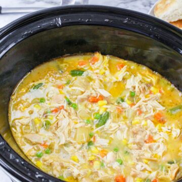Shredded chicken and vegetables in a slow cooker to make chicken pot pie.