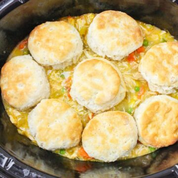 Chicken pot pie in the slow cooker with biscuits on top of the chicken and vegetables.