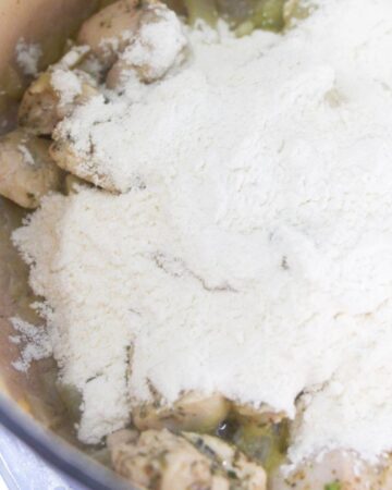 Browned chicken topped with flour in a stockpot.