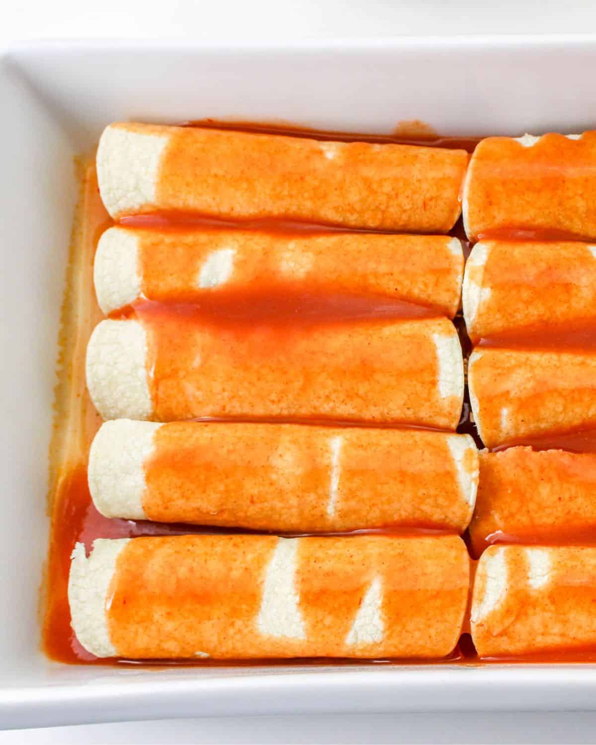 Corn tortillas rolled and stuffed with shredded beef and topped with enchilada sauce to make beef enchiladas.