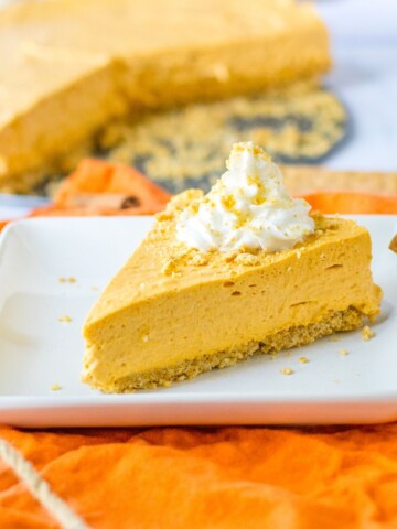 Pumpkin Pie cheesecake, a no bake dessert with whipped cream on top on a square dessert plate.