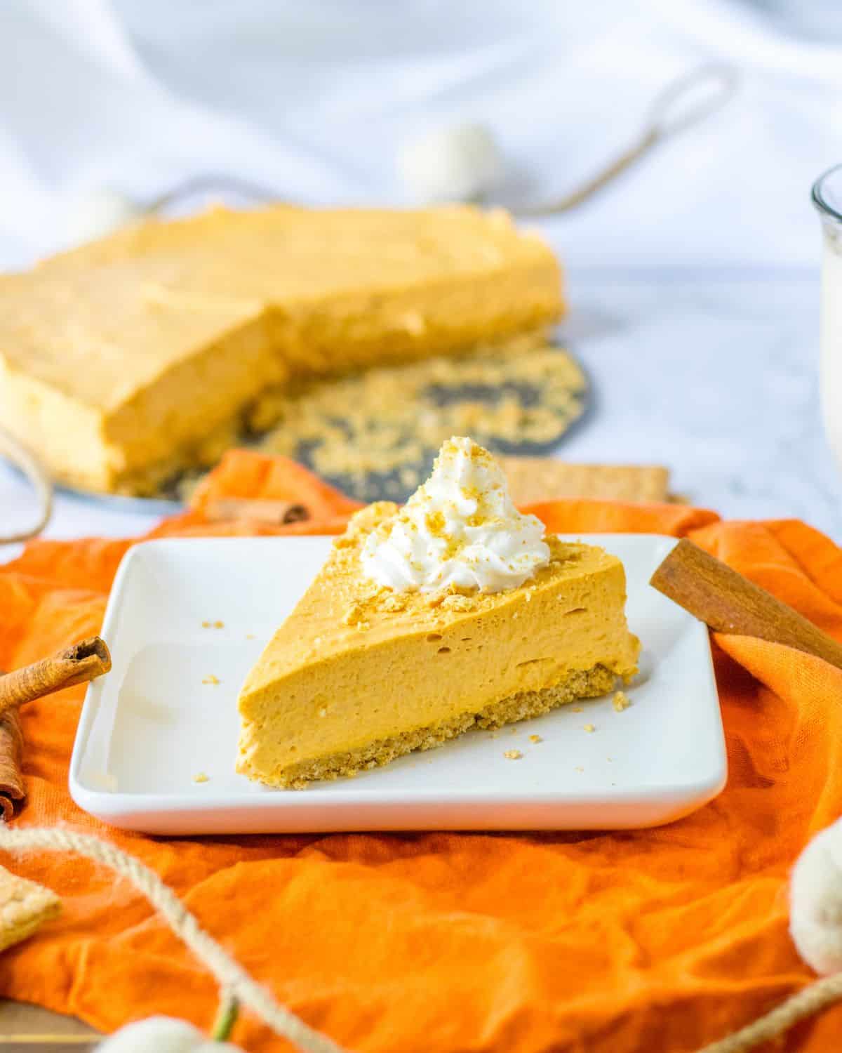 A slice of pumpkin no bake pie on white dessert plate with an orange napkin.