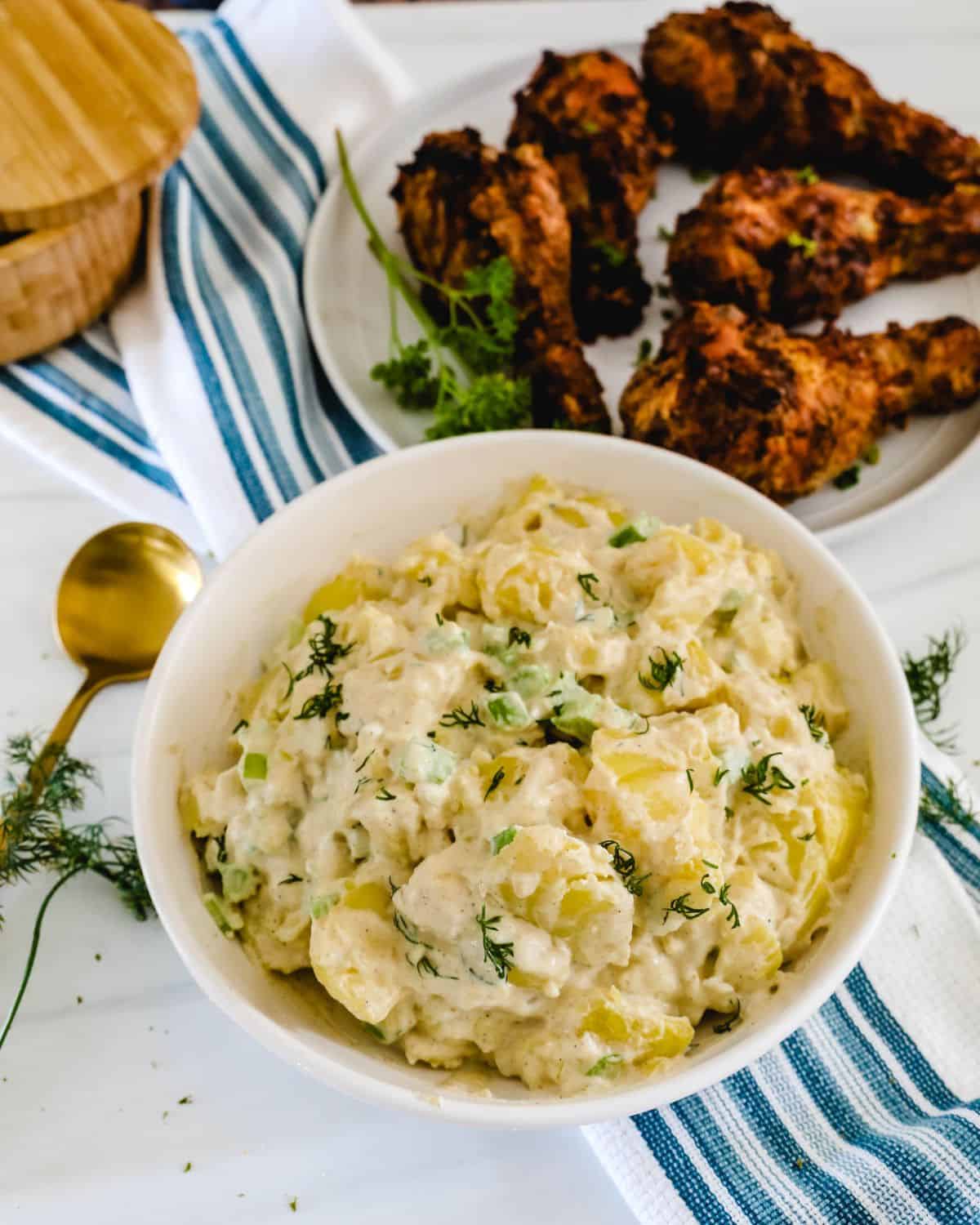 A large white bowl of potatoes in a creamy mayonaise dressing.