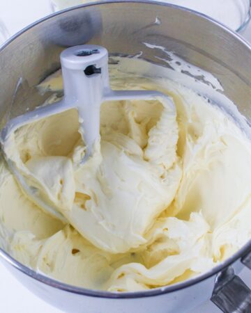 A stand mixer mixing bowl with cream cheese blended in the bowl.