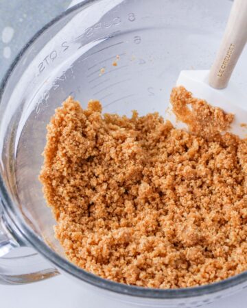 A glass bowl with graham crackers to make the crust for pecan pie bars.