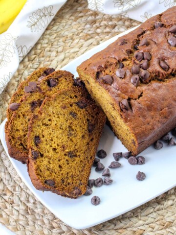 Pumpkin banana bread sliced on a plate with chocolate chips on the side.
