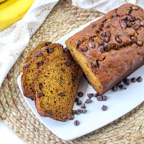 Pumpkin banana bread sliced on a plate with chocolate chips on the side.