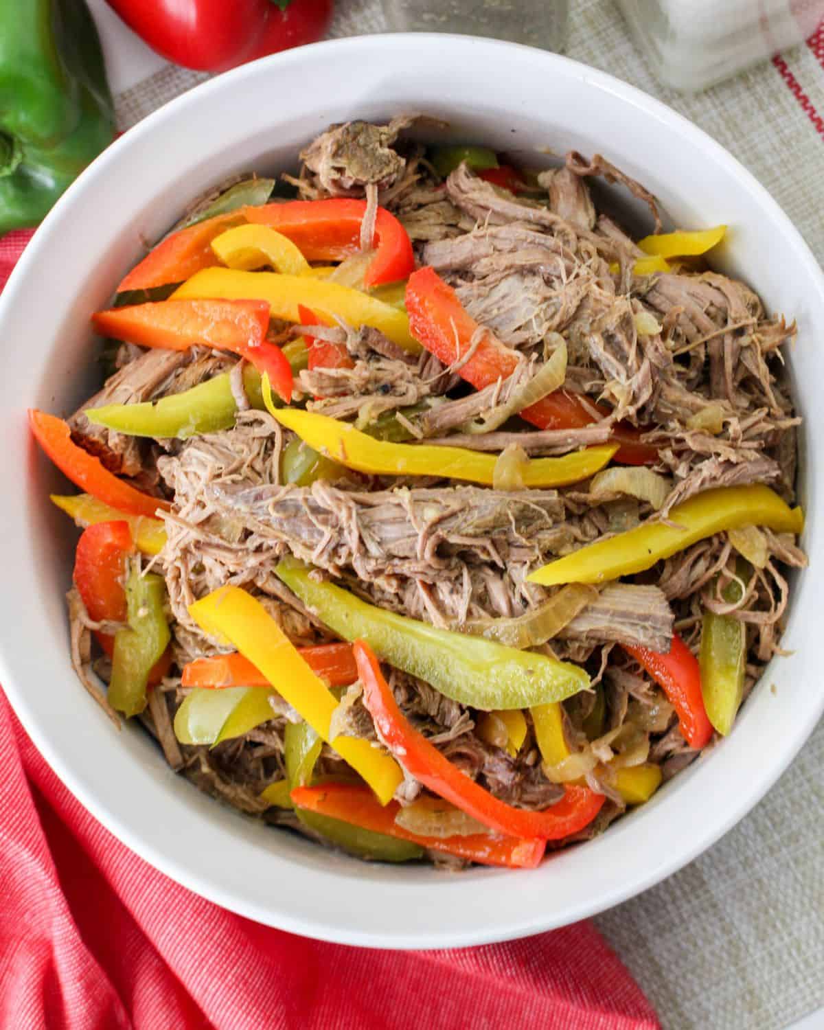 Shredded beef and peppers in a bowl made in a slow cooker.