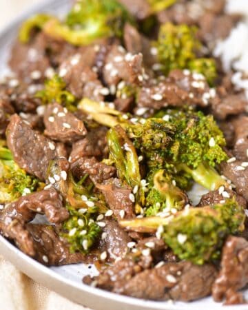 stir fry beef and broccoli topped with sesame seeds on a plate.