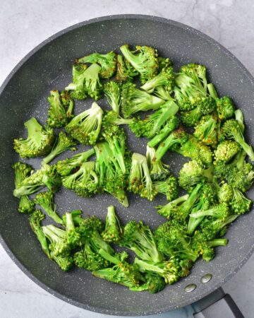 A saute pan with chopped broccoli in the pan.