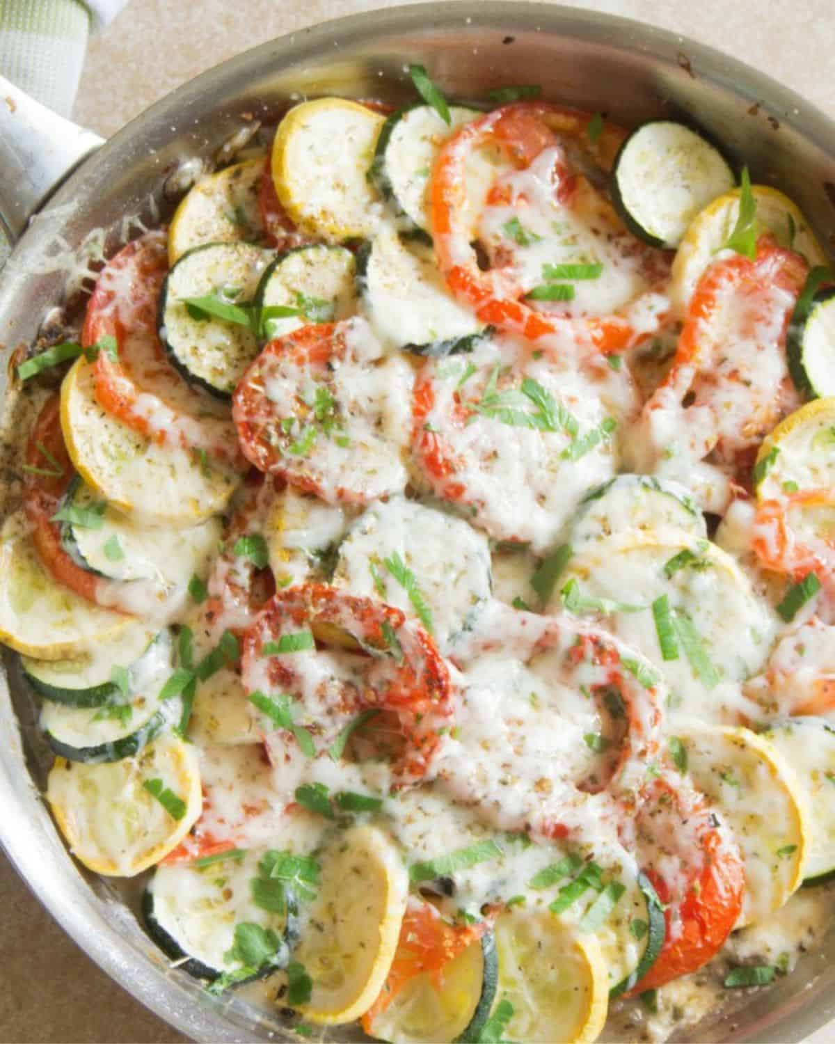 A veggie bake with eggplant, zucchini, and tomatoes topped with mozzarella cheese. 