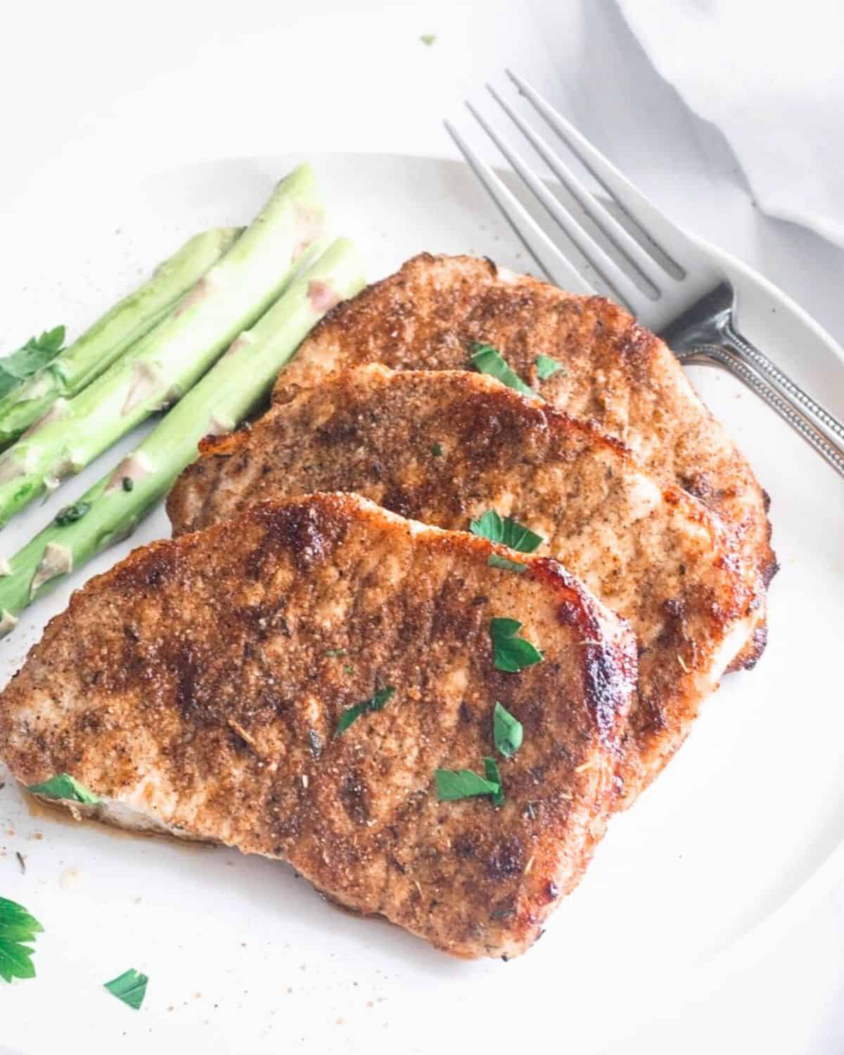 Pork chops in a dry rub that were made in the air fryer with asparagus on the side. 