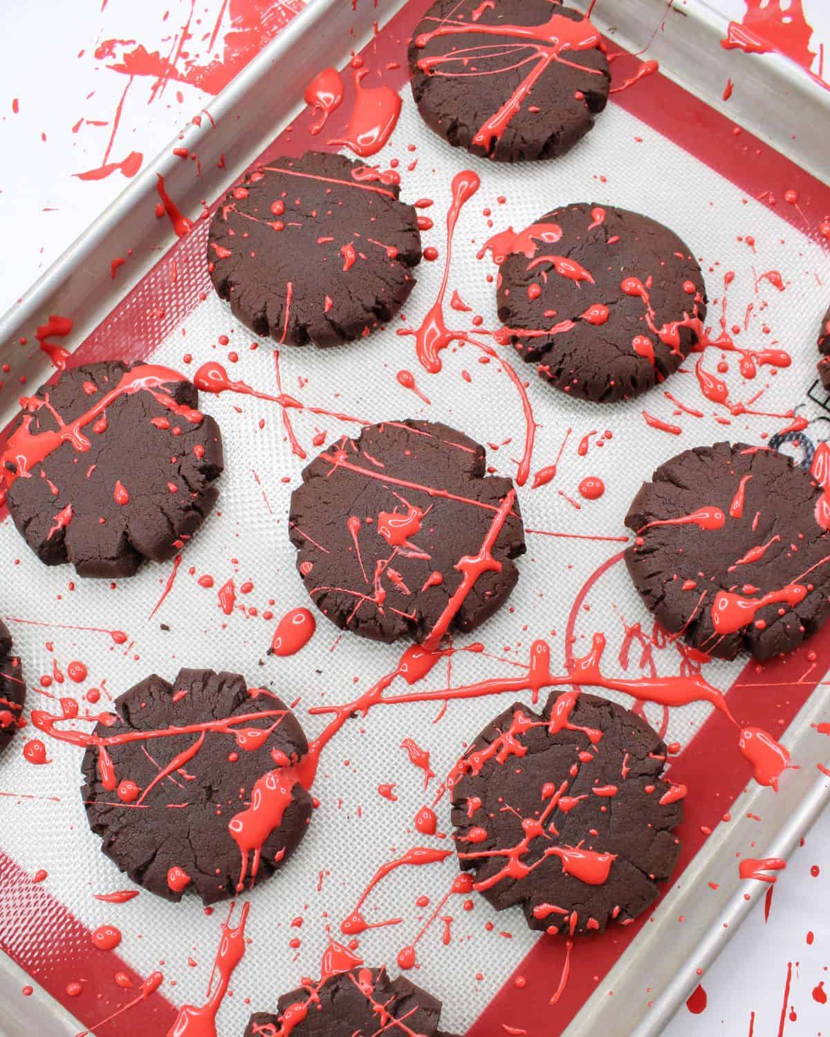 Chocolate cookies with a red splatter of frosting to mimic blood for blood splatter cookies.