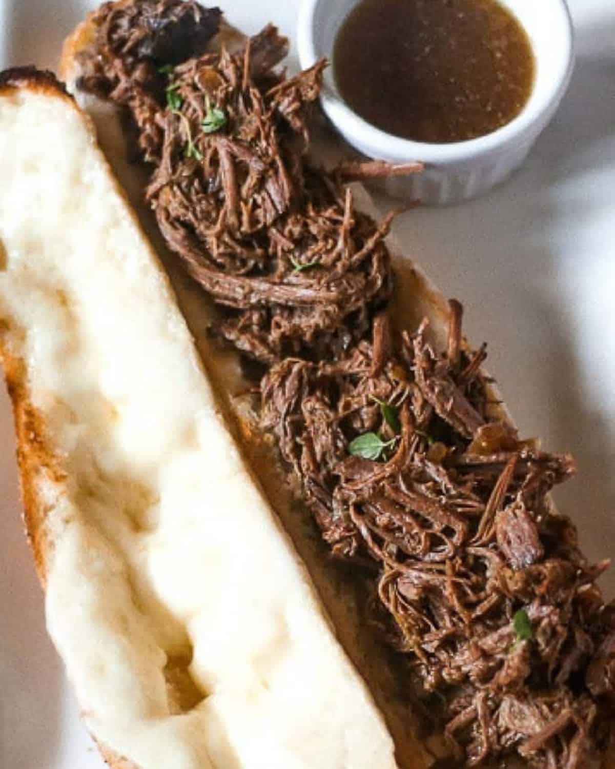 Slow cooker french dips on hoagie bread with melted provolone cheese and au jus dip.