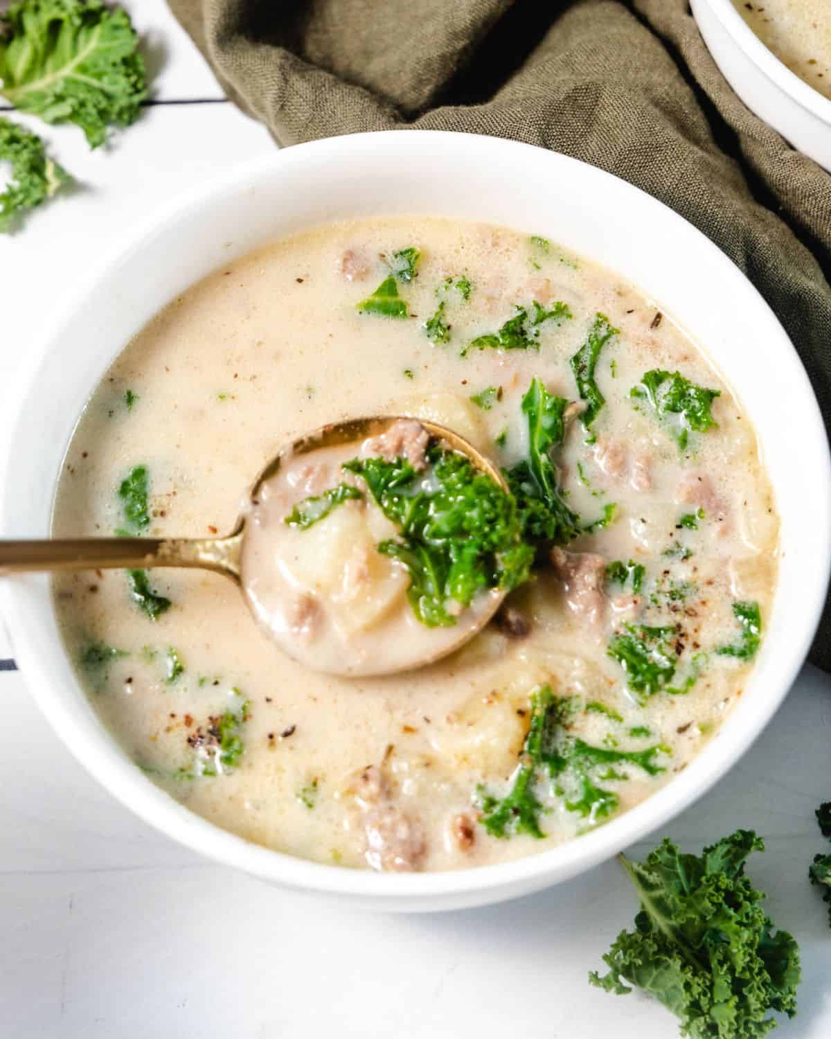 A bowl of zuppa toscana soup made with a spoon in the bowl.