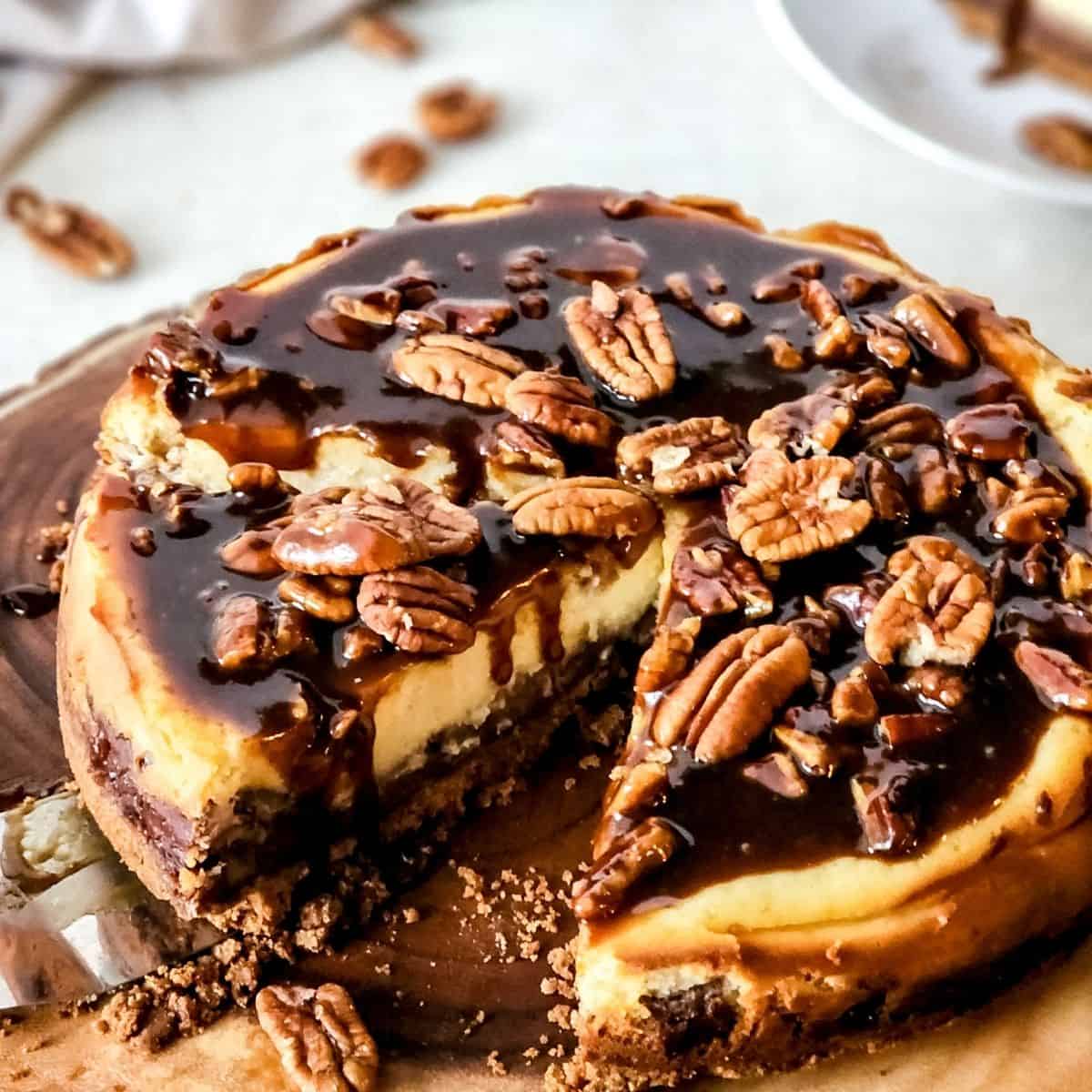 A pecan cheesecake pie with a slice of the cheesecake cut out.