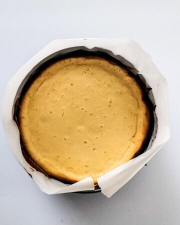 A baked cheesecake in a springform pan to make pecan pie cheesecake.