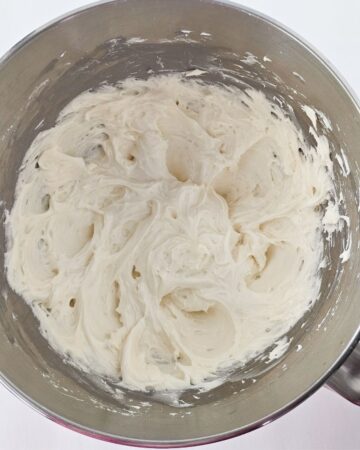 A stainless steel mixing bowl with a peppermint cream in the bowl.