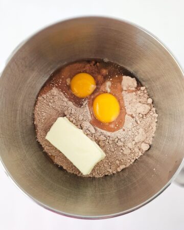 A large mixing bowl with chocolate cake mix, butter, and eggs in the bowl.