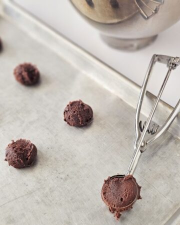 A baking sheet with chocolate cookie dough rounds on the sheet.