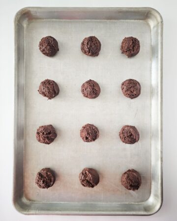 A baking sheet with chocolate sandwich cookie dough rounds on the baking sheet.