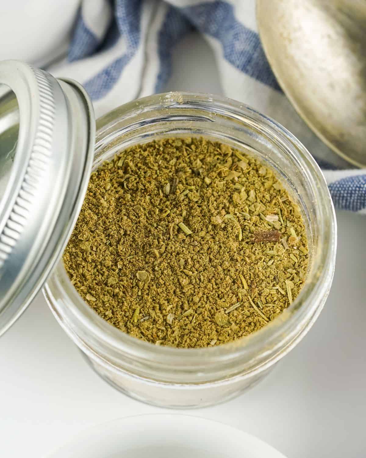 A glass mason jar with homemade poultry seasoning in the jar.