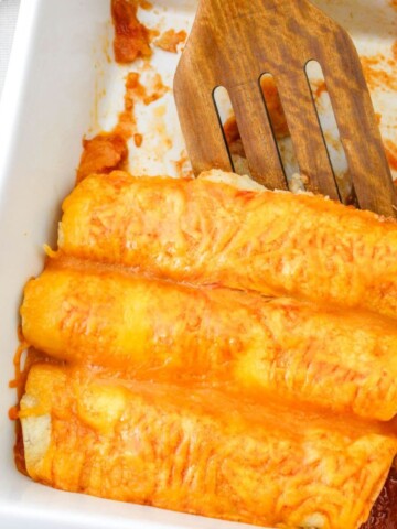 Shredded beef enchiladas in a white casserole.