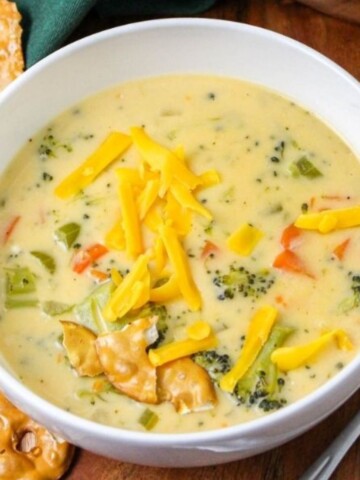 A bowl of broccoli beer cheese soup with shredded cheese.