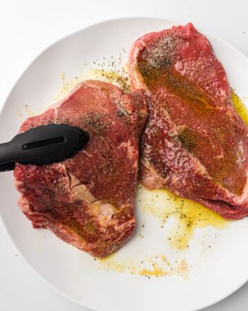 Rib eye steaks with olive oil and seasoning ready to be air fried.