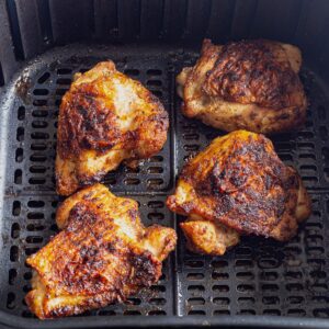 Chicken thighs made in the air fryer in the air fryer basket.