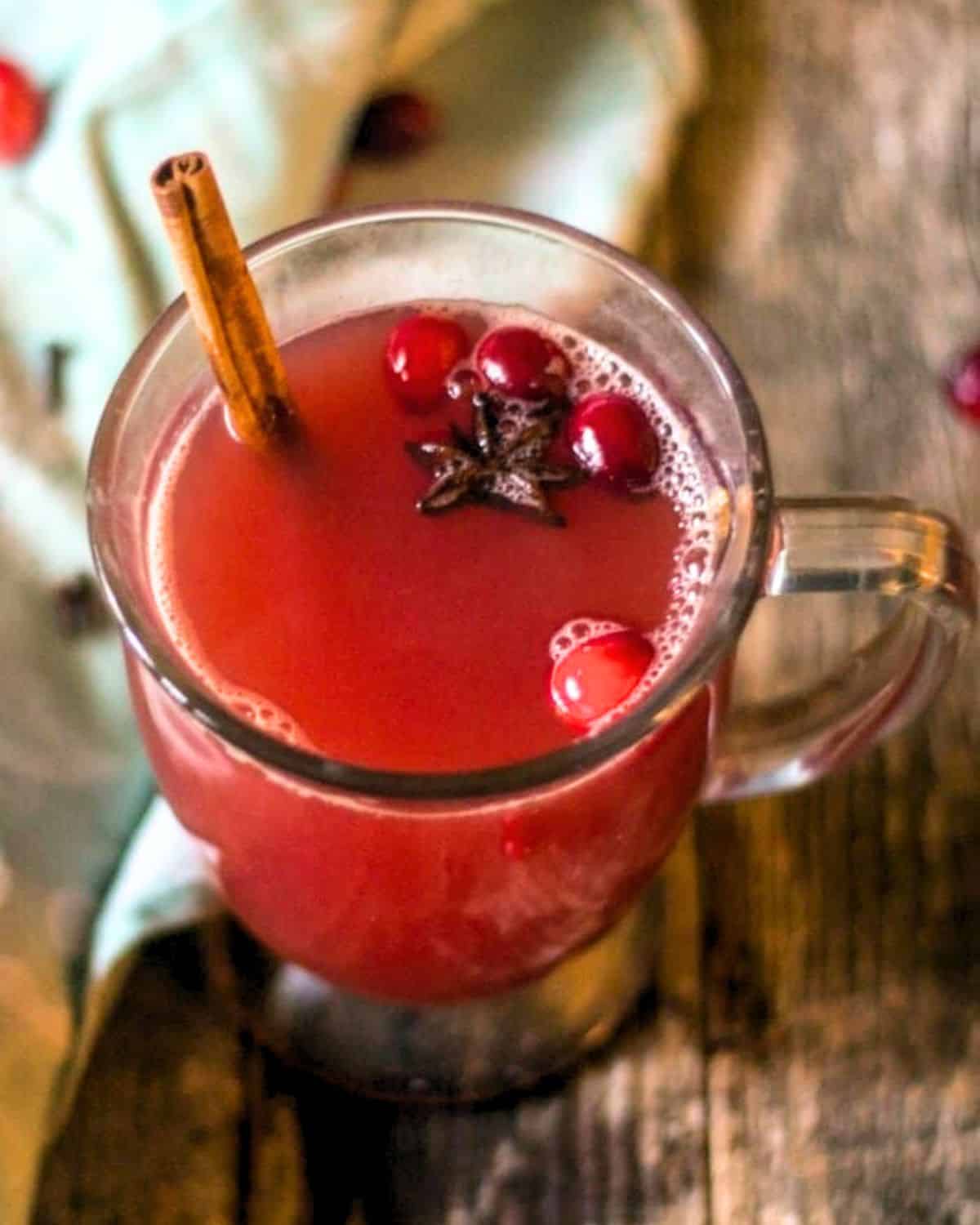 An overhead view of cranberry punch with a star anise and cranberries in the mug.