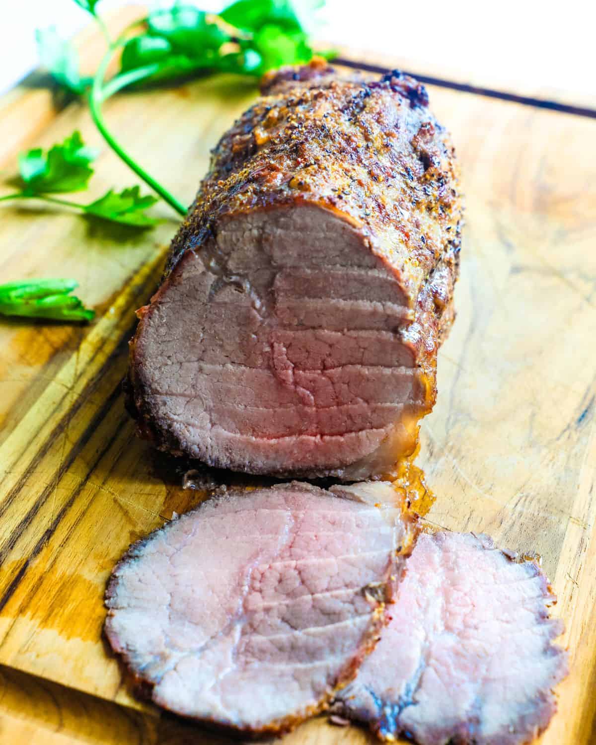 An eye of round roast sliced on a cutting board.